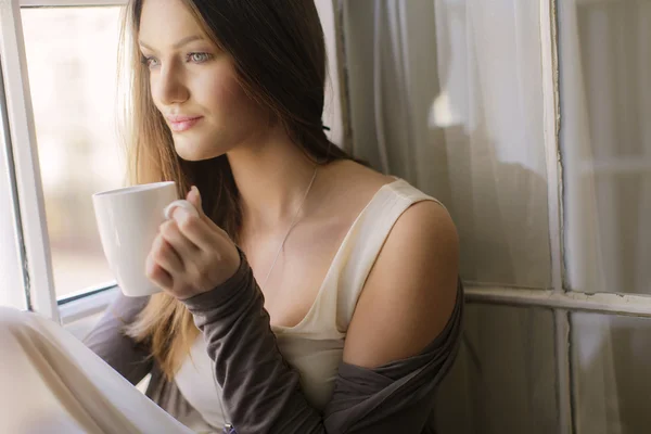 Mujer joven y bonita junto a la ventana — Foto de Stock