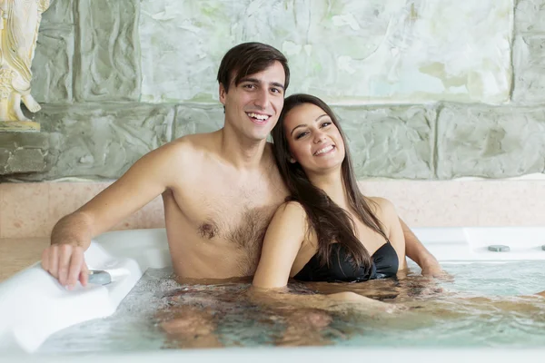 Casal jovem relaxante na banheira de hidromassagem — Fotografia de Stock