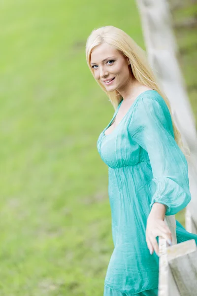 Young blond woman by the fence — Stock Photo, Image