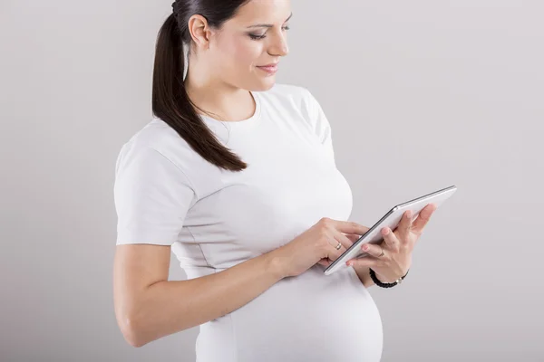 Mladá těhotná žena s tabletem — Stock fotografie