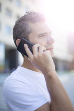 Genç adam cep telefonuyla konuşuyor.