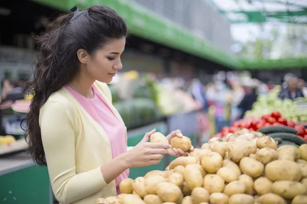 Bella giovane donna che compra verdure sul mercato Immagine Stock