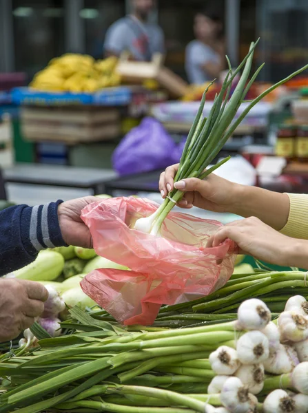 Молодая женщина покупает овощи на рынке — стоковое фото