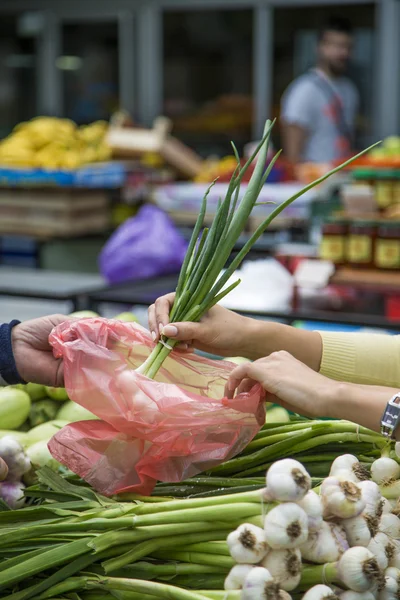 Ung kvinna köpa grönsaker på marknaden — Stockfoto