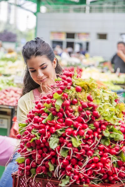 Красивая девушка покупает овощи на рынке — стоковое фото