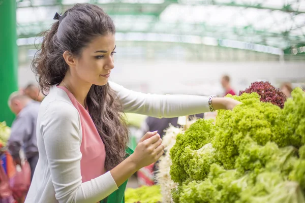 Jolie jeune femme achetant des légumes sur le marché — Photo