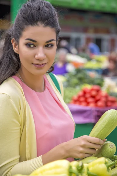 Красивая девушка покупает овощи на рынке — стоковое фото