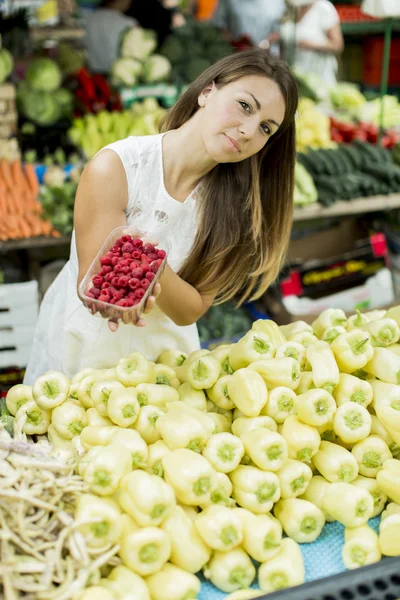 Mladá žena koupí maliny na trhu — Stock fotografie