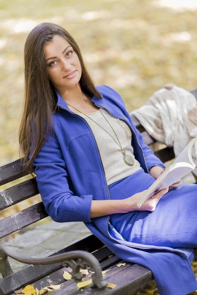 Ung kvinna läser en bok i parken — Stockfoto