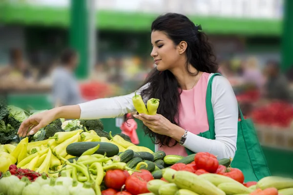 Jolie jeune femme achetant des légumes sur le marché — Photo