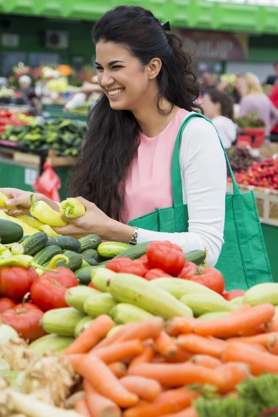 Jolie jeune femme achetant des légumes sur le marché — Photo