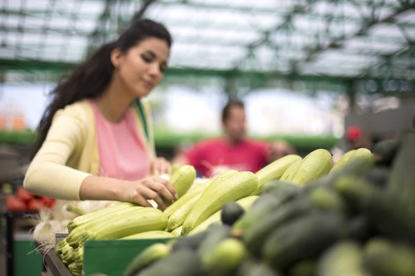 かなり若い女性が市場に野菜を買う — ストック写真