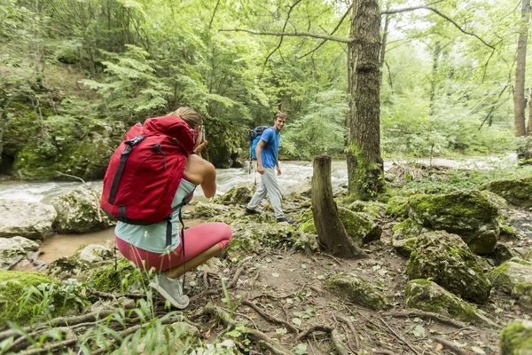 Young woman taking photo of man at hiking — Stock Photo, Image