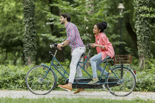 Pareja joven montando en la bicicleta tándem — Foto de Stock