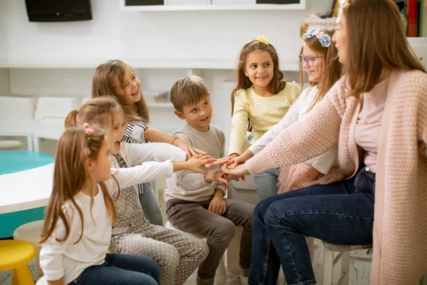 Gruppe Süßer Vorschulkinder Legt Mit Ihrer Kindergärtnerin Hand — Stockfoto