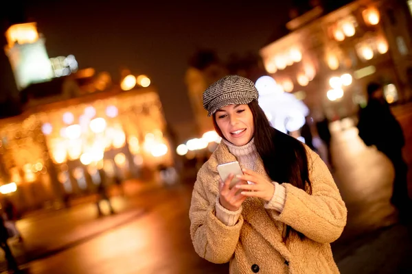 圣诞节期间 漂亮的年轻女子在街上用她的手机 — 图库照片