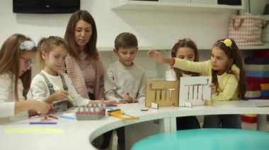 Anaokulu öğretmeniyle ahşap oyuncaklarla oynayan bir grup çocuk.