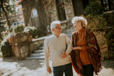 Güz parkında yürüyen yakışıklı yaşlı çift.