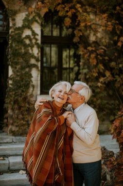 Güz parkında kucaklaşan yakışıklı yaşlı çift.