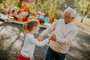 Büyükbaba eğlence parkında küçük tatlı torunuyla eğleniyor.