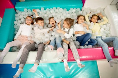 Top havuzunda eğlenirken mutlu bir şekilde gülümseyen bir grup çocuk.
