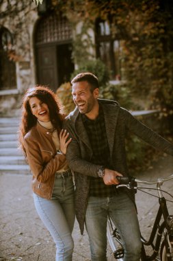 Güz parkında bisikletle yürüyen yakışıklı genç çift.