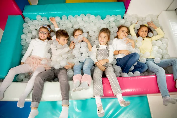 Top havuzunda eğlenirken mutlu bir şekilde gülümseyen bir grup çocuk.