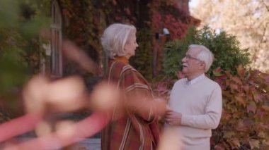 Güz parkında kucaklaşan yakışıklı yaşlı çift.