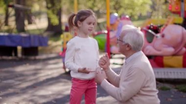 Büyükbaba eğlence parkında küçük tatlı torunuyla eğleniyor.