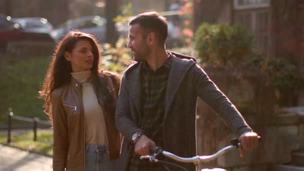 一对年轻貌美的夫妇骑着自行车在秋天的公园里散步 — 图库视频影像