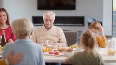Mutlu bir aile evde kırmızı şarapla yemek yiyor.