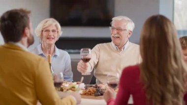 Mutlu bir aile evde kırmızı şarapla yemek yiyor.