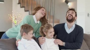 İki çocuklu mutlu bir aile. Oturma odasındaki kanepede birlikte eğleniyorlar.