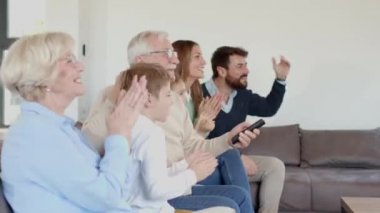 Çok nesildir TV 'de futbol seyreden ve bir golü kutlayan, oturma odasındaki koltukta oturan bir aile.