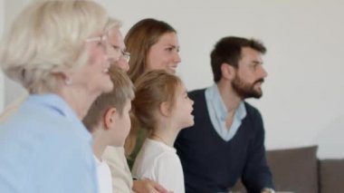 Çok nesildir TV 'de futbol seyreden ve bir golü kutlayan, oturma odasındaki koltukta oturan bir aile.