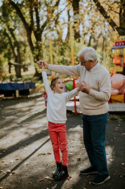 Büyükbaba eğlence parkında küçük tatlı torunuyla eğleniyor.