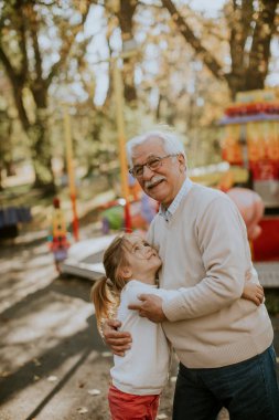 Büyükbaba eğlence parkında küçük tatlı torunuyla eğleniyor.