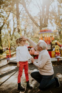 Büyükbaba eğlence parkında küçük tatlı torunuyla eğleniyor.