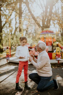 Büyükbaba eğlence parkında küçük tatlı torunuyla eğleniyor.