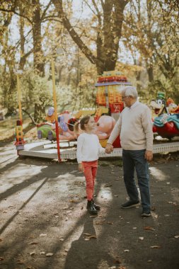 Büyükbaba eğlence parkında küçük tatlı torunuyla eğleniyor.