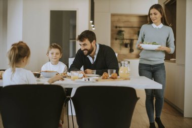 Genç anne modern mutfakta ailesine kahvaltı hazırlıyor.