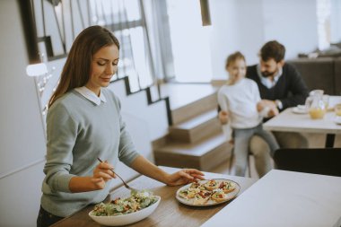 Genç anne modern mutfakta ailesine kahvaltı hazırlıyor.