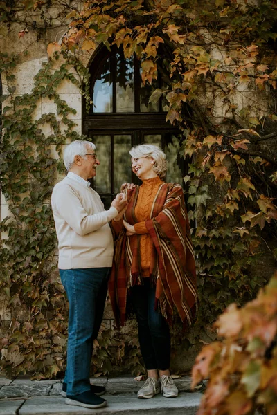 Güz parkında kucaklaşan yakışıklı yaşlı çift.