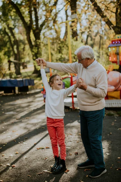 Büyükbaba eğlence parkında küçük tatlı torunuyla eğleniyor.