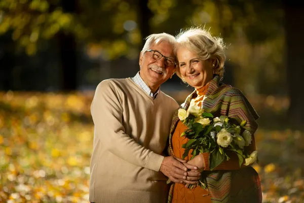 Bonito Casal Sênior Abraçando Com Buquê Flores Parque Outono — Fotografia de Stock