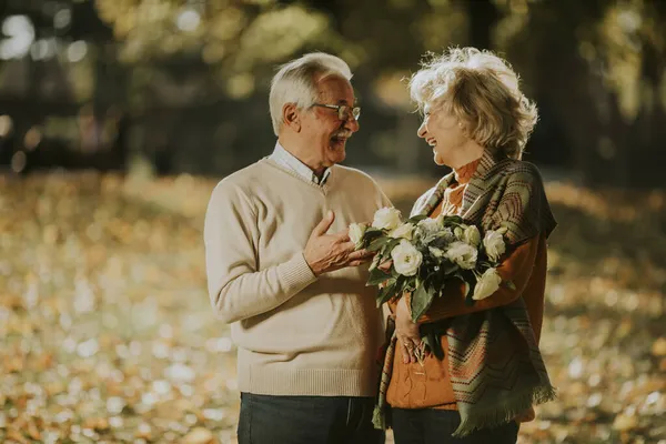 Stilig Senior Par Omfamna Med Blombukett Höstparken — Stockfoto