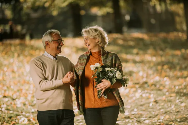 Przystojny Senior Para Obejmujący Kwiat Bukiet Jesienny Park — Zdjęcie stockowe