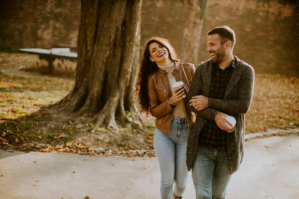 年轻貌美的一对情侣带着咖啡在秋天的公园散步 手里拿着杯子 — 图库照片
