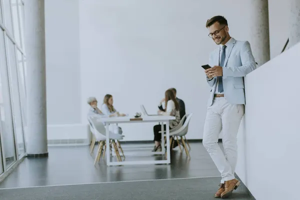 Handsome Young Man Using His Mobile Phone Office While His — Stock Photo, Image