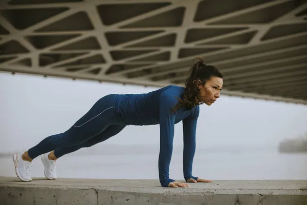 Jonge Vrouw Blauw Trainingspak Doet Push Ups Onder Brug Stedelijke — Stockfoto